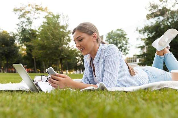 Jovem sorridente passando um tempo no parque, estudando