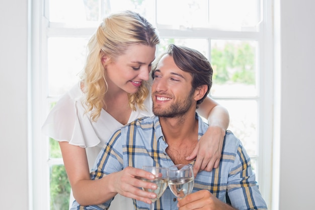 Jovem sorridente que aprecia o vinho branco juntos