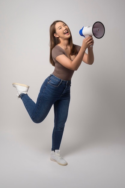 Foto jovem sorridente segurando o megafone sobre fundo branco studiox9