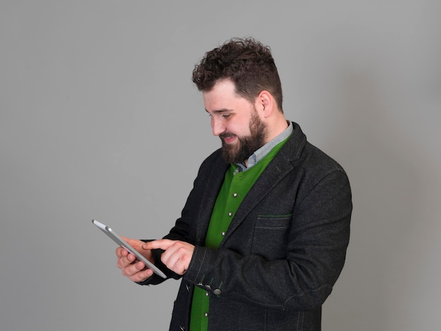 Jovem sorridente segurando um tablet digital contra um fundo cinzento