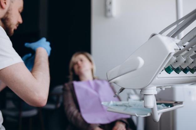 Jovem sorridente tendo seus dentes verificados pelo dentista durante a consulta na clínica odontológica