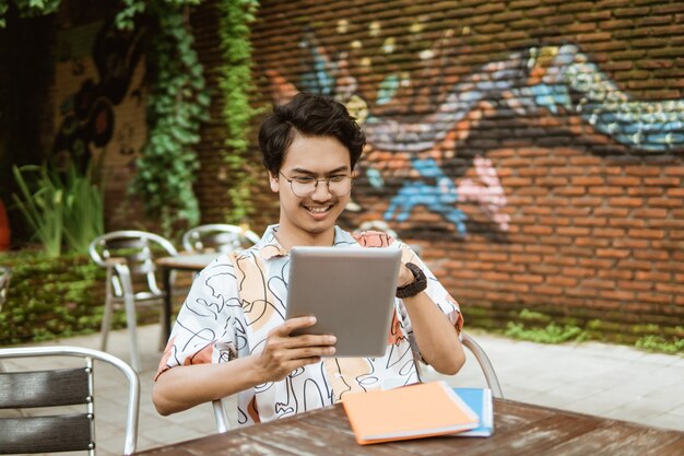 Jovem sorridente usando o tablet pc para atribuição de trabalho