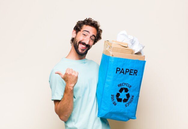 Jovem sorrindo alegre e casualmente apontando para uma cópia do espaço ao lado, sentindo-se feliz e satisfeito