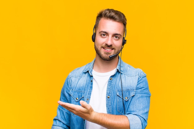 Jovem sorrindo alegremente, sentindo-se feliz e mostrando um conceito no espaço da cópia com a palma da mão