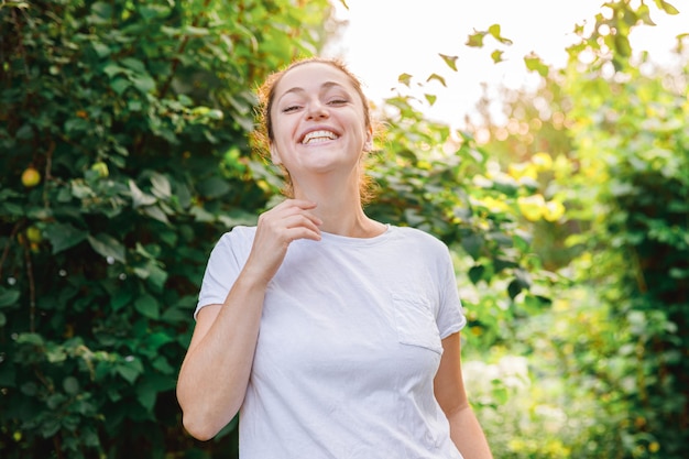 Jovem sorrindo ao ar livre. linda garota morena descansando em um parque ou jardim verde