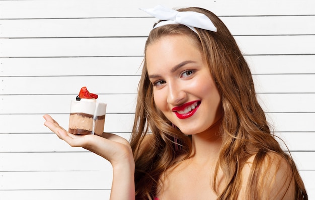 Jovem sorrindo com cupcake na mão