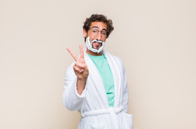 Jovem sorrindo e parecendo feliz, despreocupado e positivo, gesticulando vitória ou paz com uma mão