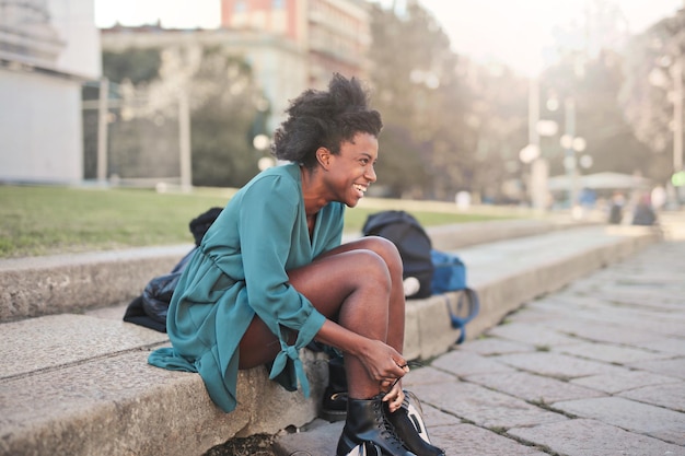 jovem sorrindo enquanto troca de sapatos na rua