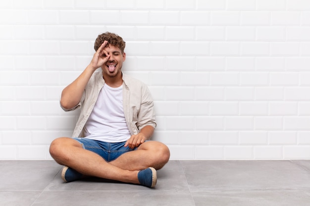 Jovem sorrindo feliz com cara engraçada, brincando e olhando pelo olho mágico, espionando segredos