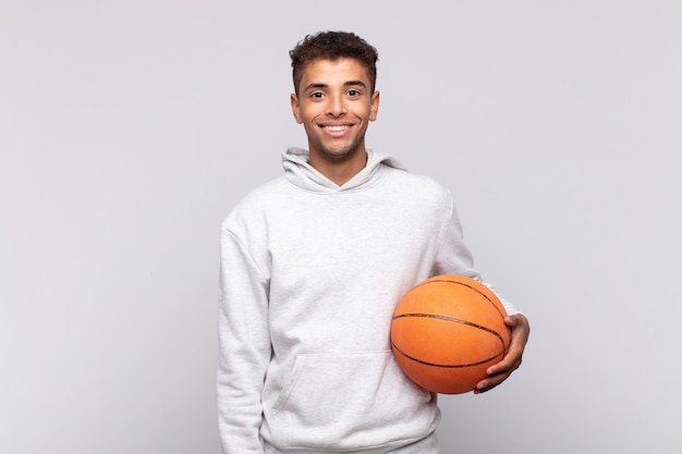 Jovem sorrindo feliz com uma mão no quadril e atitude confiante, positiva, orgulhosa e amigável. conceito de cesta