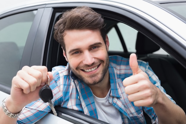 Jovem sorrindo para a câmera mostrando a chave