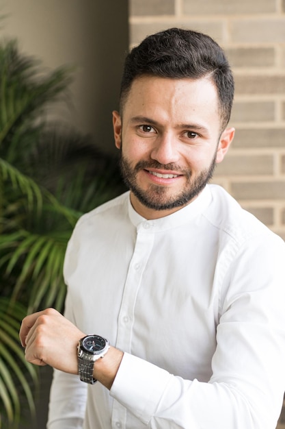 Jovem sorrindo, vestindo uma camisa branca no escritório. Retrato de um jovem colombiano