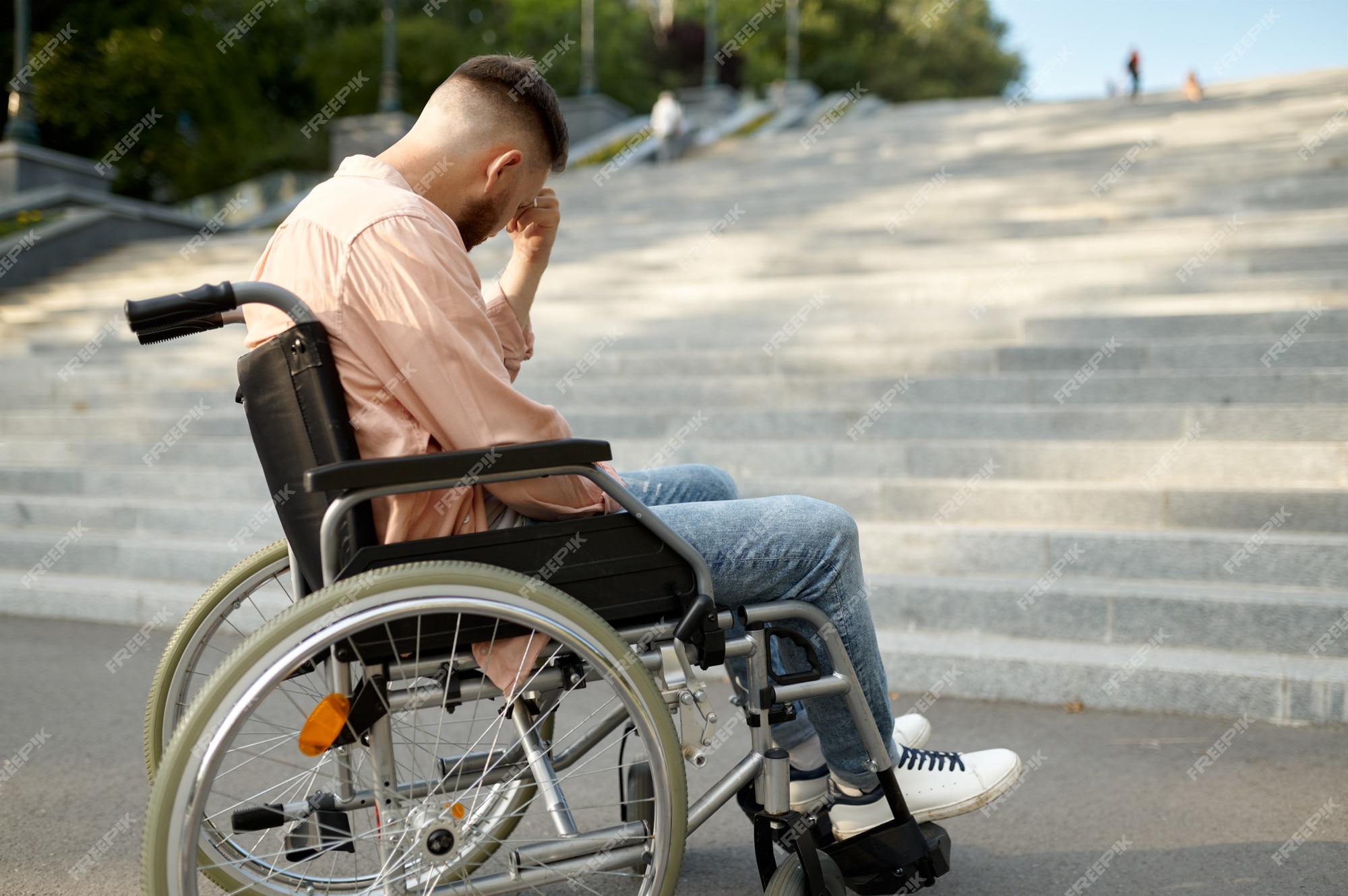 Jovem sozinho em cadeira de rodas nas escadas, problema de deficiência.  pessoas paralisadas e incapacitadas, superação de deficiências. homem  deficiente e indefeso caminhando no parque