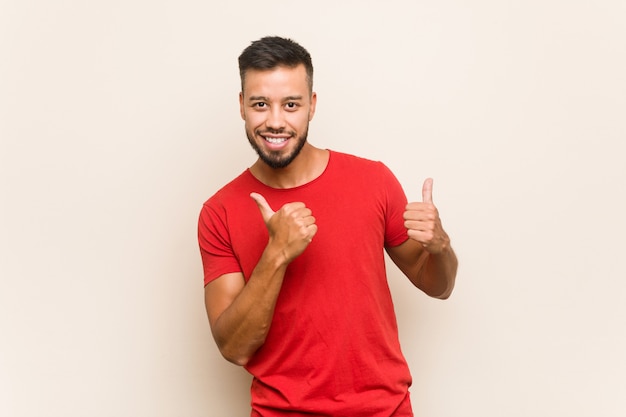 Jovem sul-asiático, levantando os dois polegares, sorrindo e confiante.