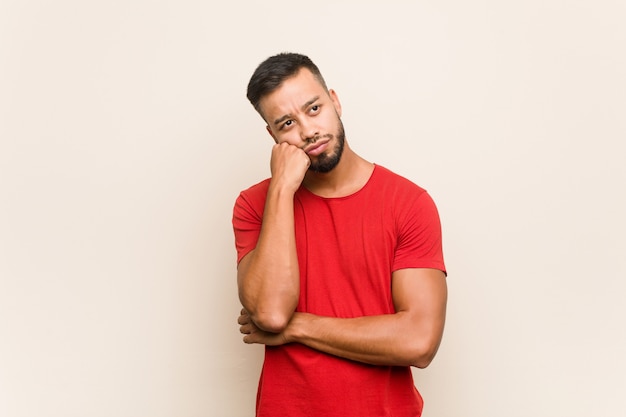 Jovem sul-asiático que se sente triste e pensativo, olhando para o espaço da cópia.