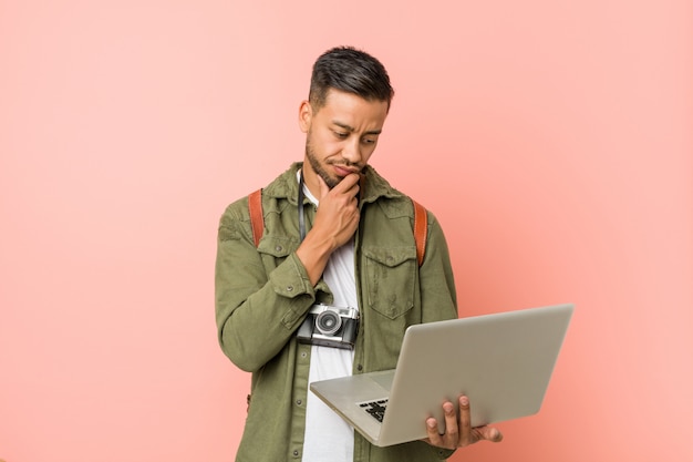 Jovem sul-asiático segurando um laptop.