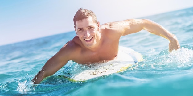 Jovem surfista boiando na água azul