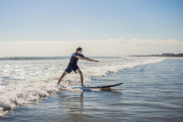 Jovem, surfista iniciante aprende a surfar em uma espuma do mar na ilha de Bali