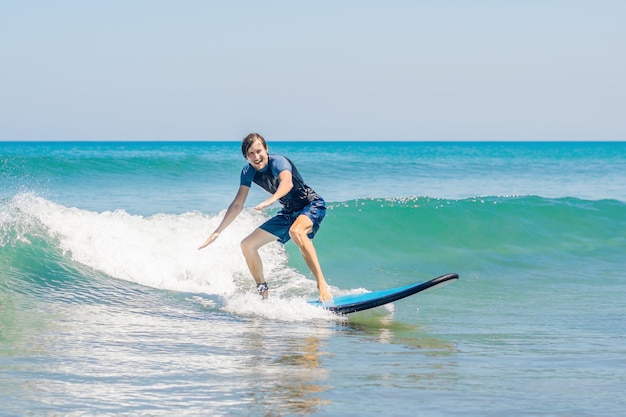 Jovem, surfista iniciante aprende a surfar em uma espuma do mar na ilha de bali