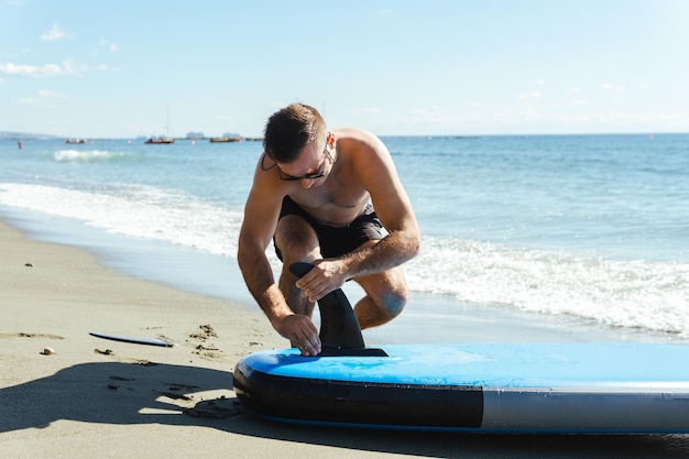 Jovem surfista masculino montando standup paddle em uma praia