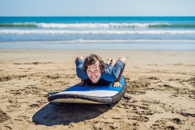 Jovem surfista treinando antes de ir para a programação em uma praia de areia. Aprendendo a surfar. Conceito de férias. Férias de verão. turismo, esporte