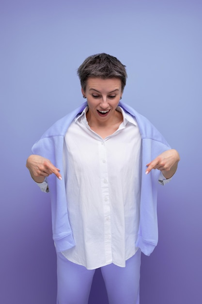 Jovem surpreendida com um corte de cabelo curto carismaticamente aponta o dedo para o espaço