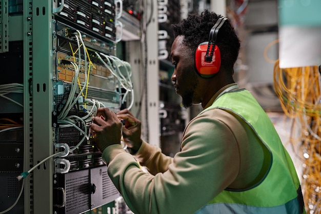 Jovem técnico configurando rede e vestindo roupas de trabalho protetoras