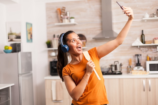 Jovem tendo um bom dia, tirando uma selfie na cozinha