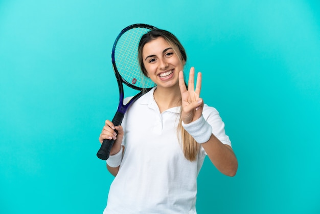 Jovem tenista isolada em um fundo azul feliz e contando três com os dedos