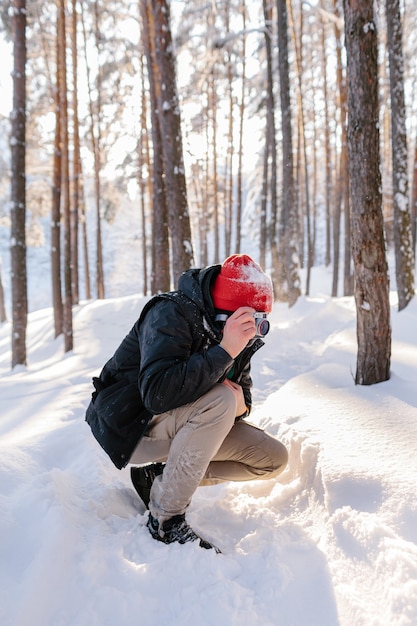 Jovem tira fotos na floresta de inverno. neve fresca