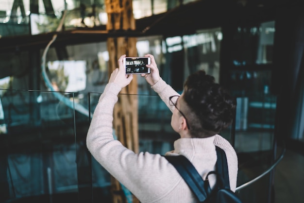 Jovem tirando foto em pé no chão com cerca de vidro