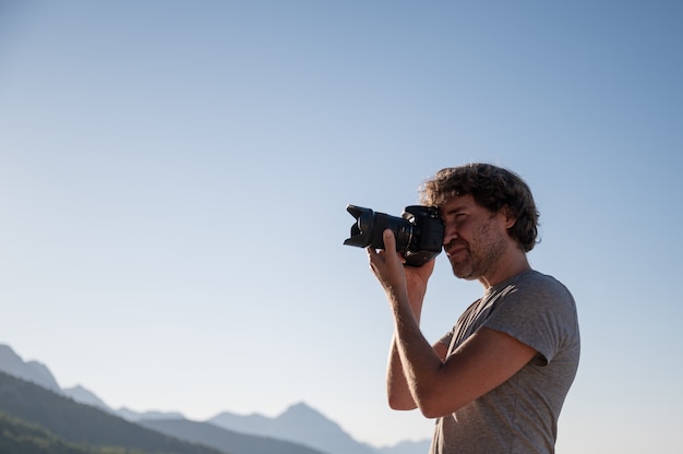 Jovem tirando fotos com uma câmera profissional dslr lá fora em uma linda manhã de verão.