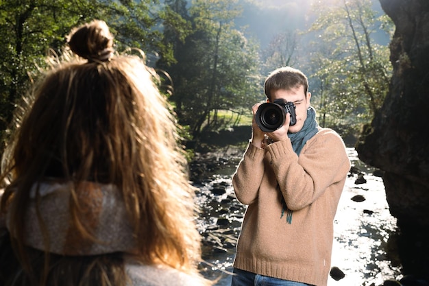 Jovem tirando fotos para um modelo ao ar livre em um parque