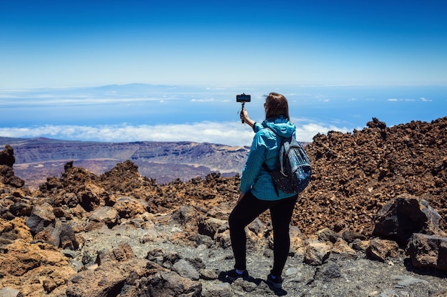 Jovem tirando uma foto com seu telefone da incrível paisagem de montanhas em Tenerife Ilhas Canárias Espanha Conceito de viagem