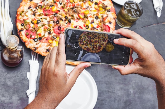 jovem tirando uma foto no restaurante de sua pizza com seu celular