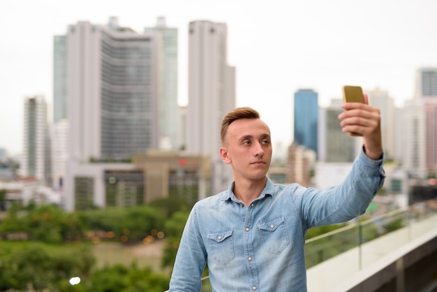 Jovem tirando uma selfie com o celular na cidade