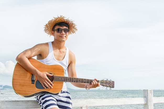 Jovem tocando violão na praia