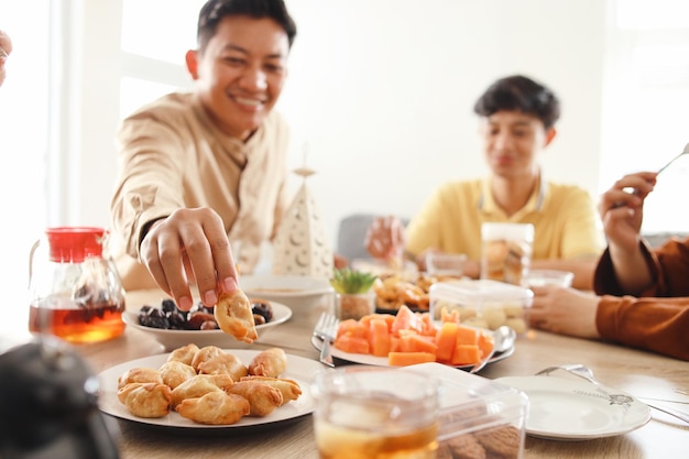 Jovem tomando biscoitos do prato durante o iftar no Ramadan conceito de pequeno-almoço