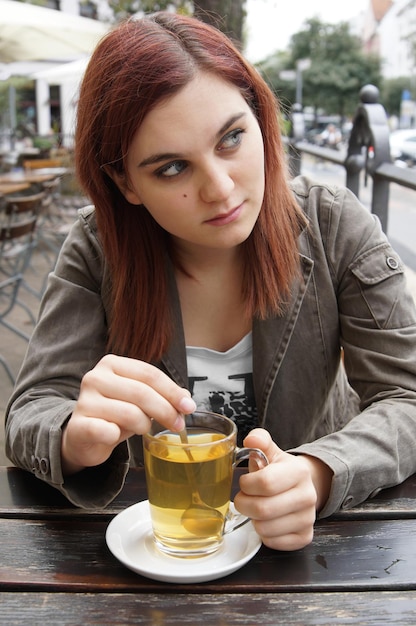 jovem tomando chá em um café de rua