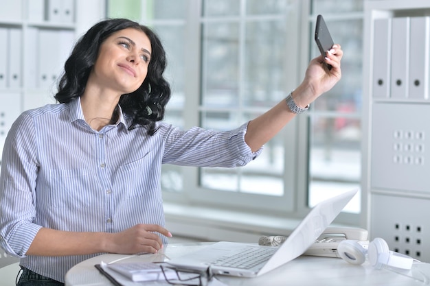 Jovem tomando selfie no local de trabalho