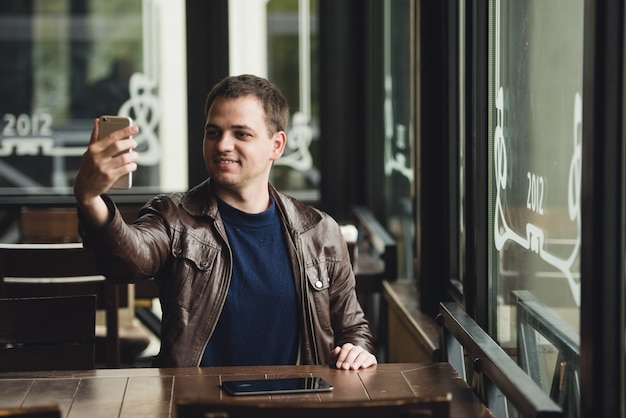 Foto jovem tomando uma selfie em uma cafeteria