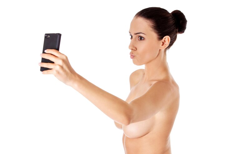 Foto jovem topless tirando uma selfie de um telefone celular contra um fundo branco