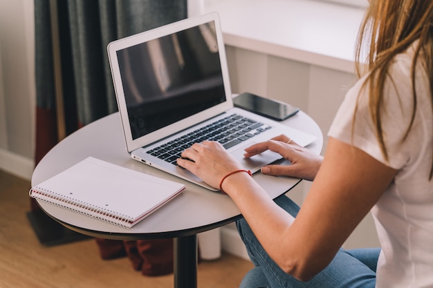 Jovem trabalha ou estuda em casa com seu laptop