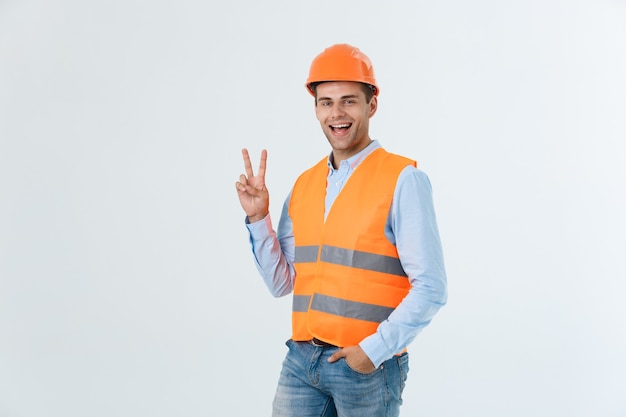 Jovem trabalhador com capacete feliz e contando dois com os dedos sobre fundo verde