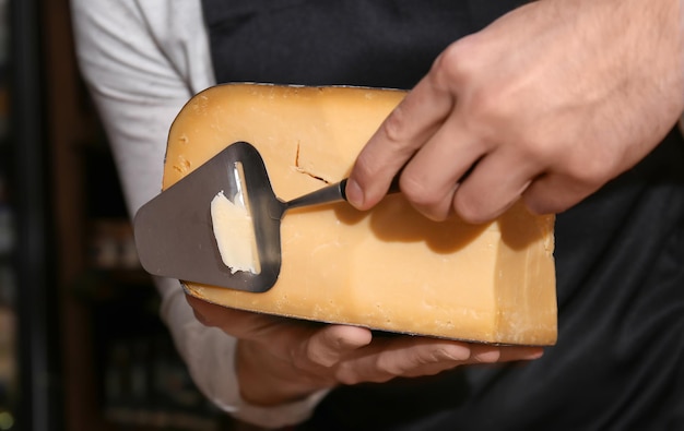 Jovem trabalhador cortando queijo na loja