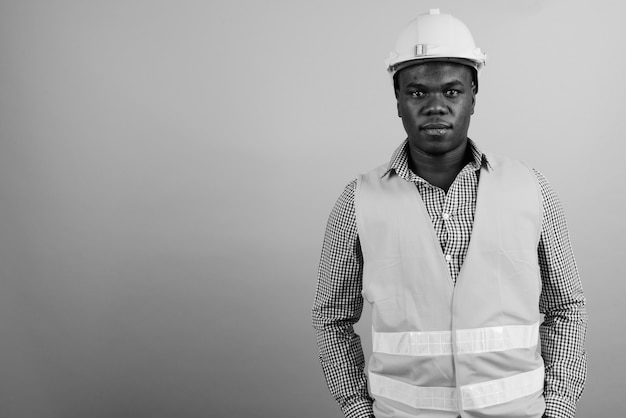 jovem trabalhador da construção civil africano contra uma parede branca. Preto e branco