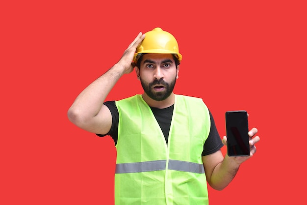 jovem trabalhador da construção civil chocando segurando um telefone modelo indiano do Paquistão