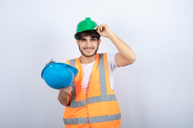 Jovem trabalhador da construção civil com capacete de segurança em pé sobre fundo branco. foto de alta qualidade