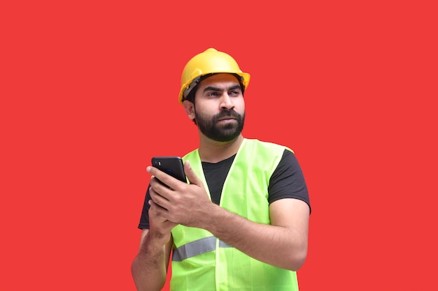 jovem trabalhador da construção civil segurando o telefone com as duas mãos modelo indiano do paquistanês