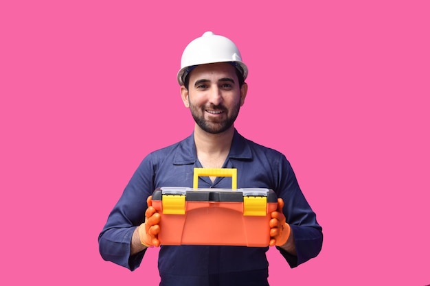 jovem trabalhador da construção civil sorrindo e segurando a caixa de ferramentas modelo indiano do paquistanês